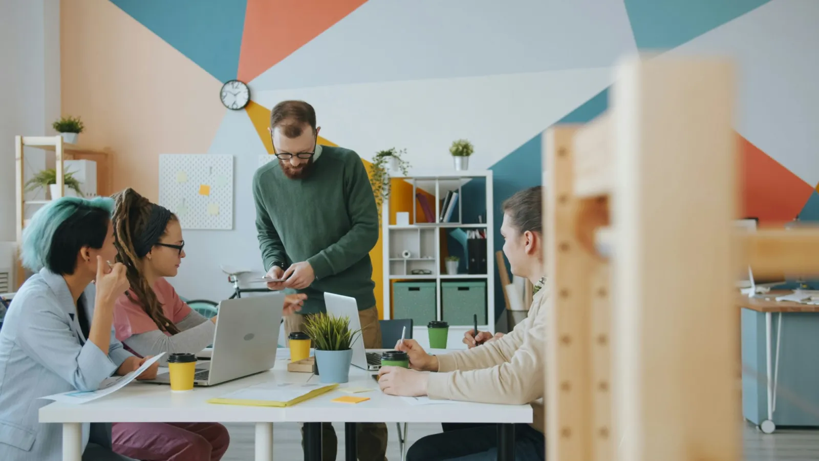 Ein Team bespricht sich an einem Tisch mit Laptops und Unterlagen